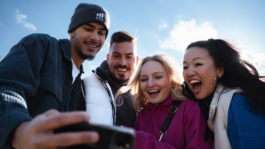 Vier junge Menschen schauen sich etwas auf dem Smartphone an