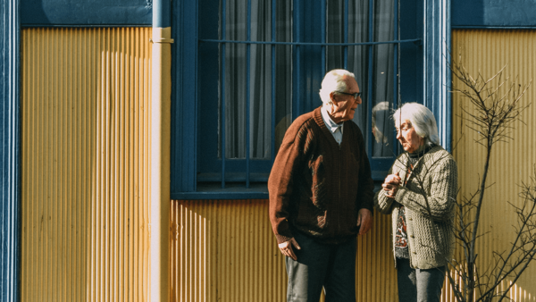 Älteres Pärchen steht vor einem Haus – Demografischer Wandel  