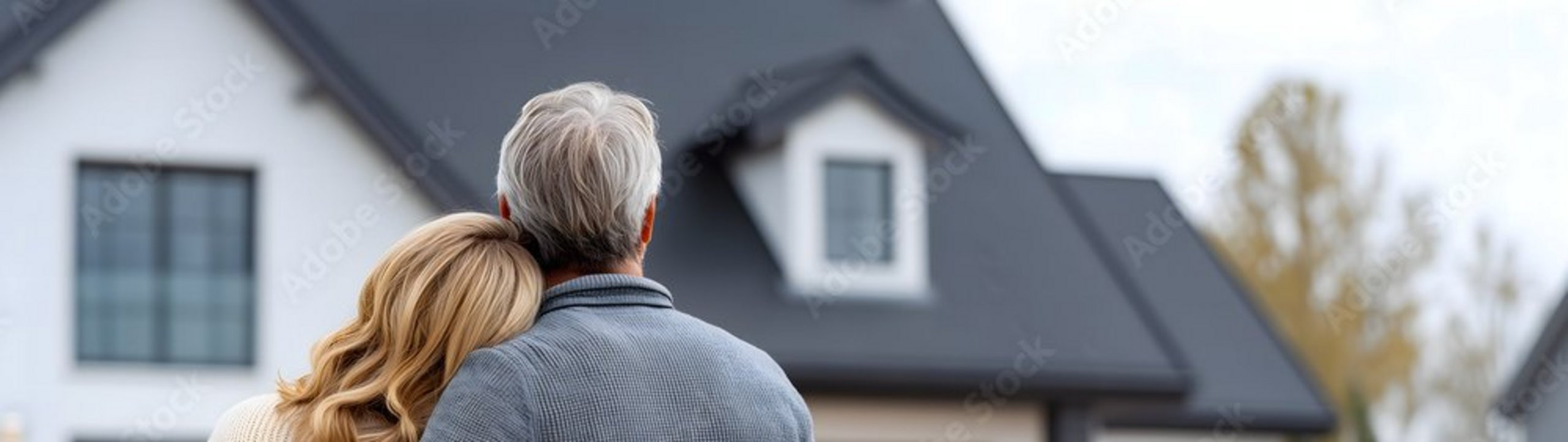 Ein Paar umarmt sich und blickt auf ein Einfamilienhaus