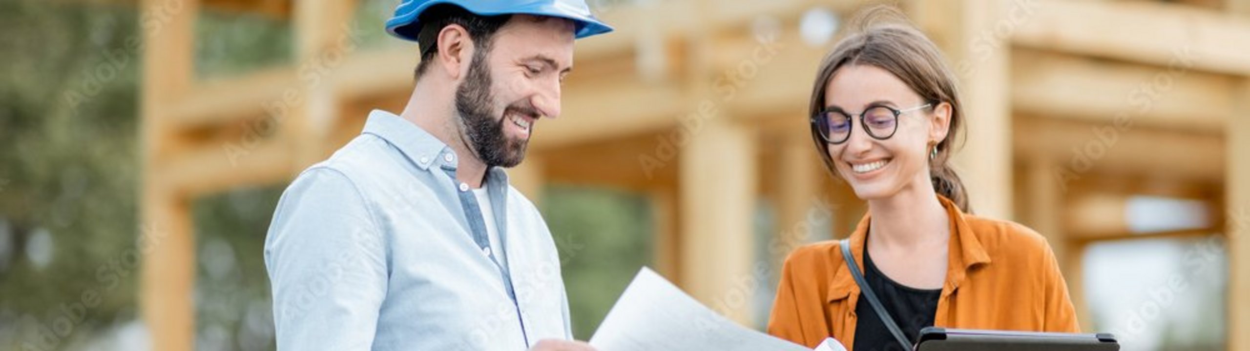 Zwei Fachkräfte prüfen Baupläne auf einer Baustelle.