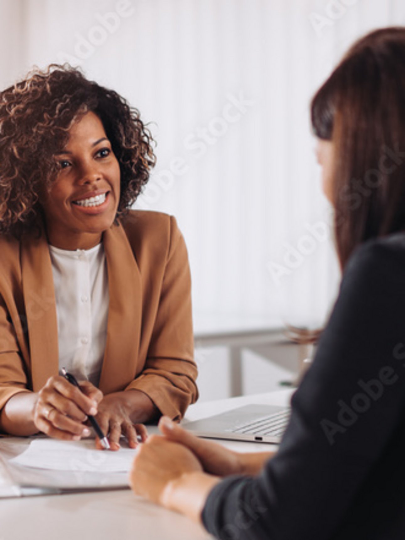Zwei Frauen sitzen sich bei einem Beratungsgespräch am Schreibtisch gegenüber.