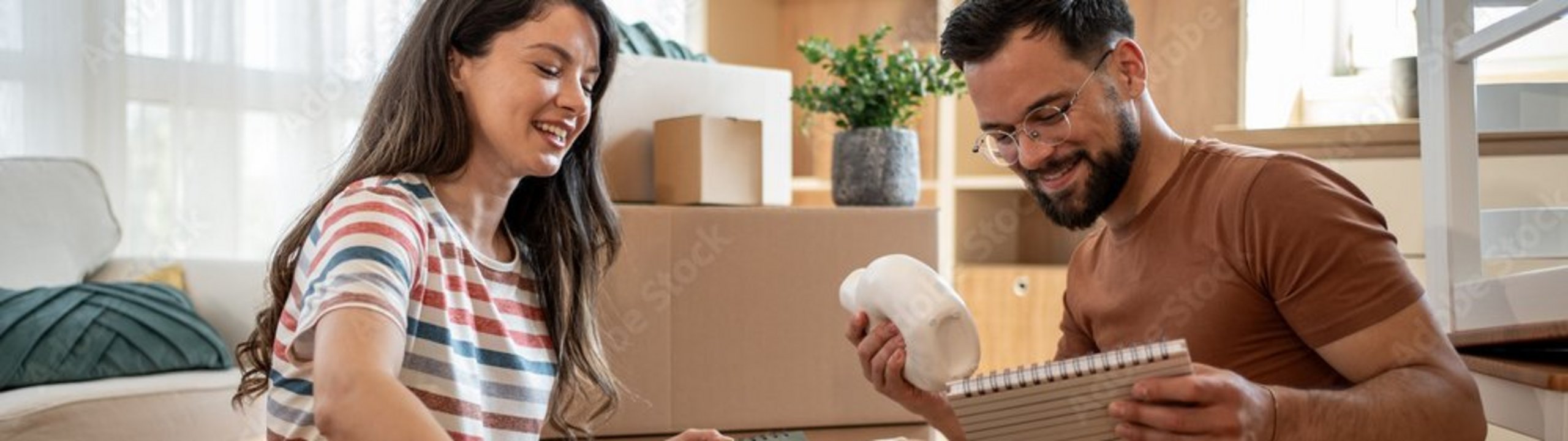 Paar packt Umzugskartons in einer neuen Wohnung aus.