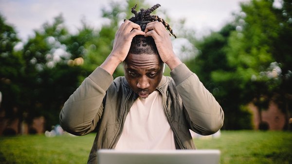 Man slaps hands over head in front of notebook - Error culture Man slaps hands over head in front of notebook - Error culture