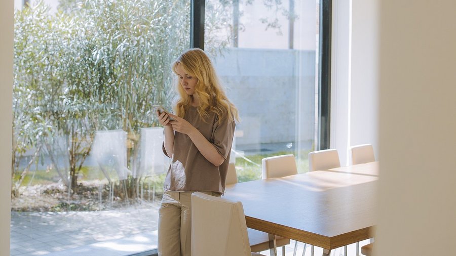 Woman leaning at the table and looking at her mobile phone – gender pay gap 