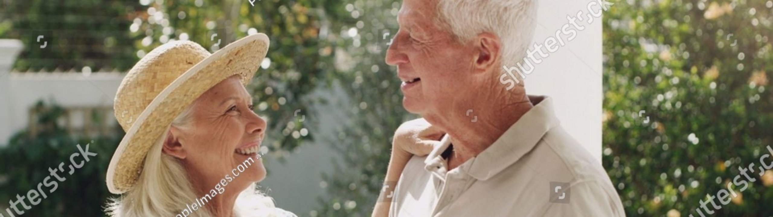 Älteres Paar lächelt sich im Garten liebevoll an.