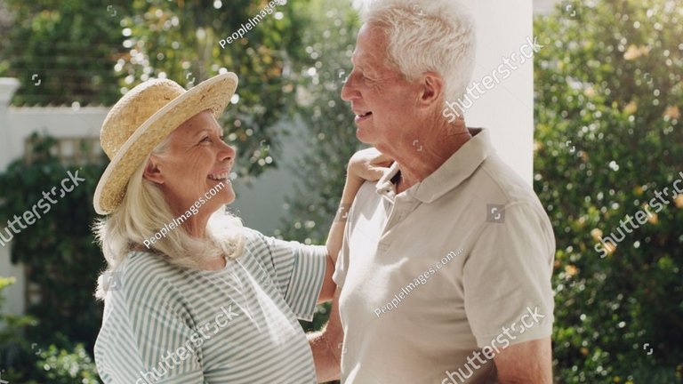 Älteres Paar lächelt sich im Garten liebevoll an.