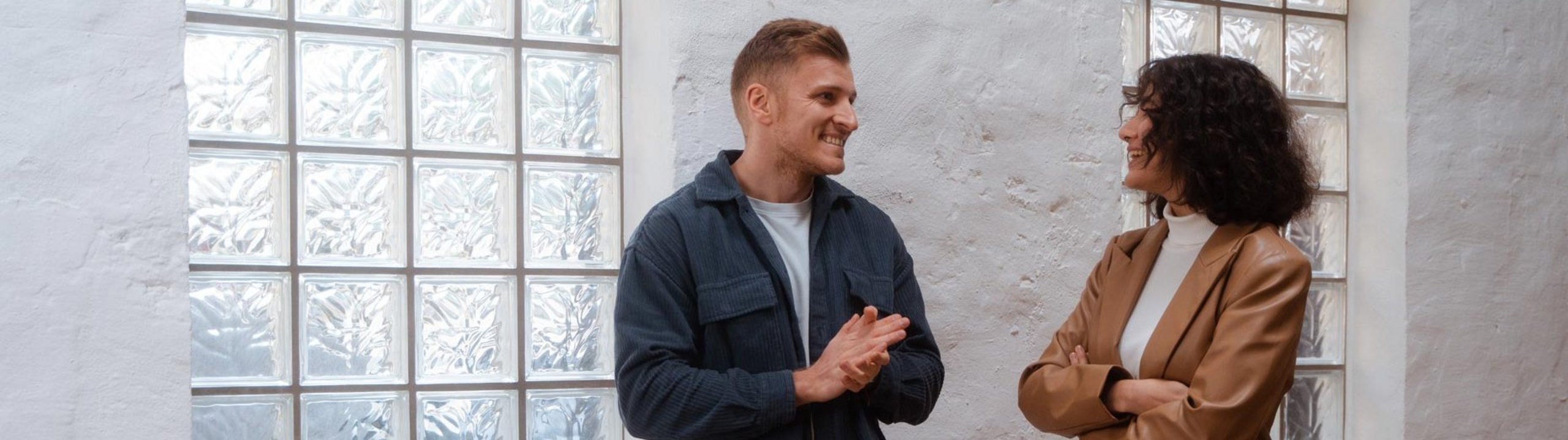 Zwei Personen unterhalten sich lächelnd in einem modernen Raum.