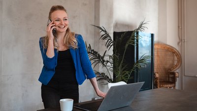 Woman laughing and phoning at work