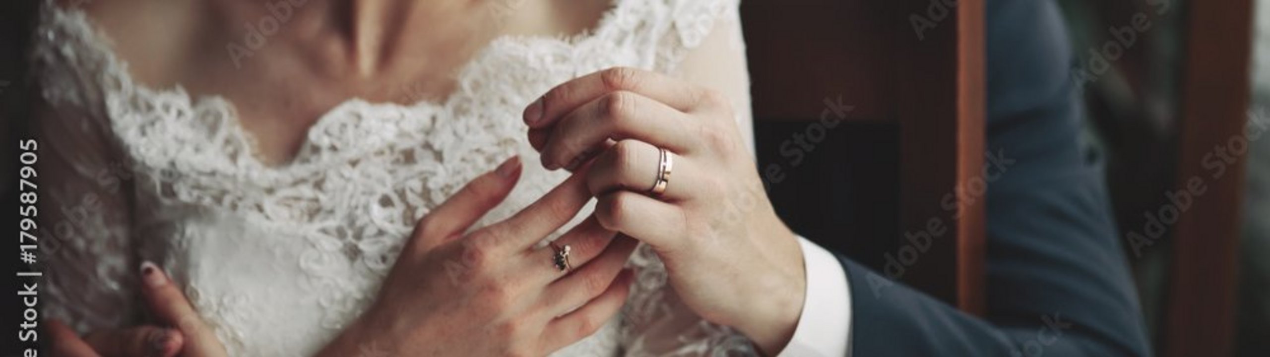 Ein Brautpaar, das sich umarmt, während ihre Hände mit Eheringen sichtbar sind.