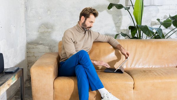 Mann arbeitet mit Tablet auf der Couch – Work-Life-Integration   