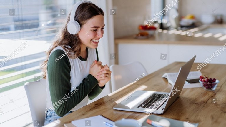 Lächelnde Frau am Laptop mit Kopfhörern auf