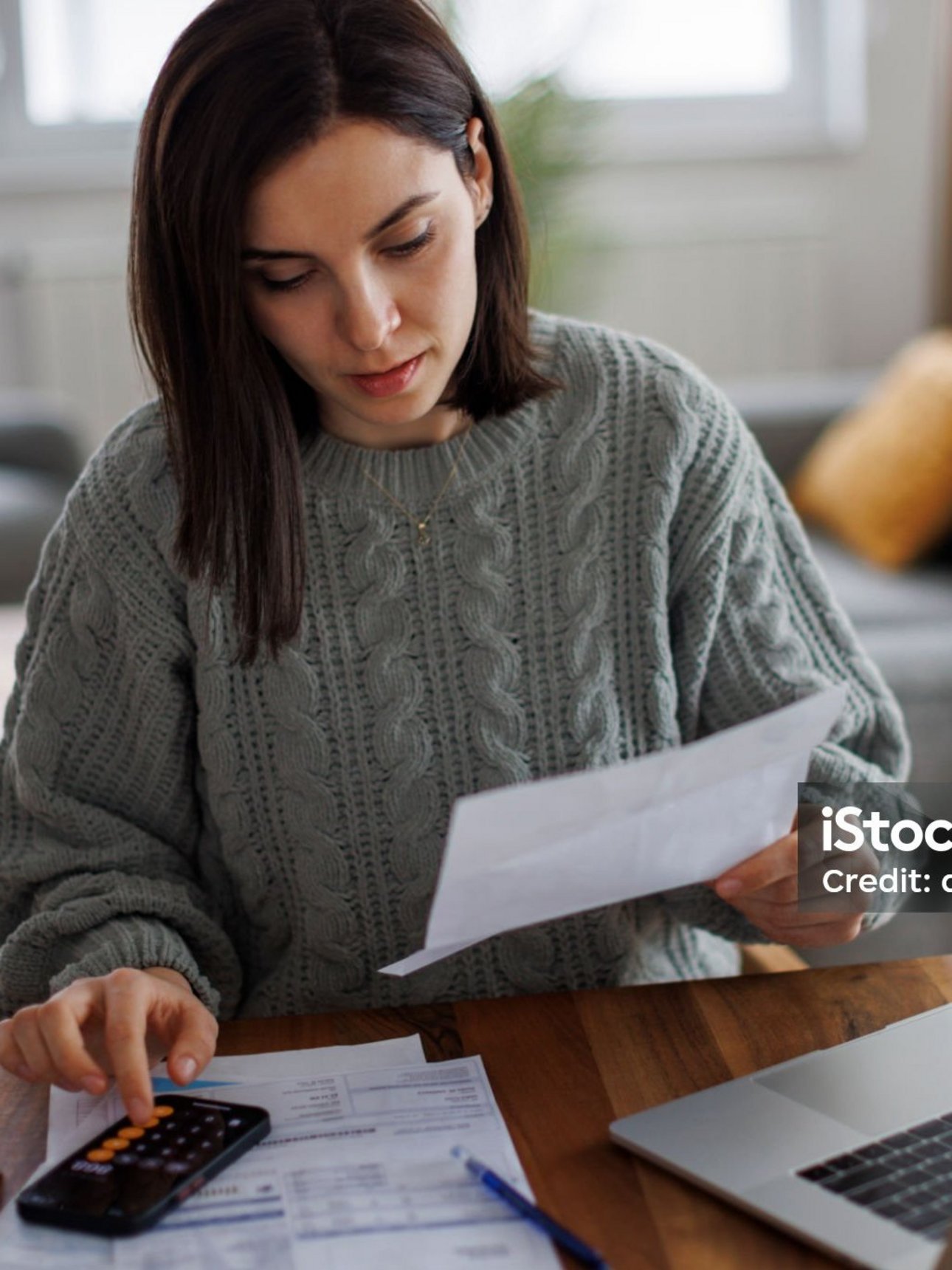 Frau am Taschenrechner mit Unterlagen in der Hand