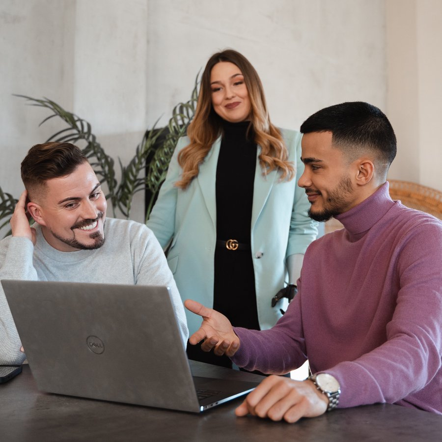 Drei Personen besprechen gemeinsam etwas am Laptop.