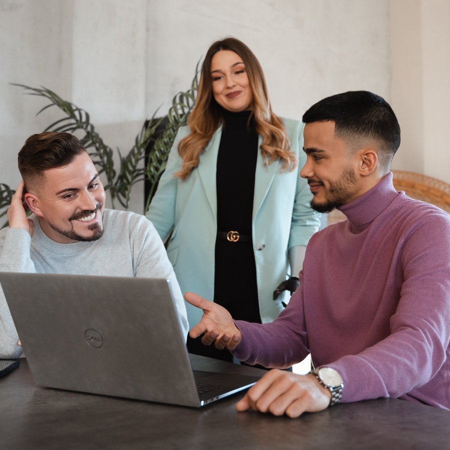 Drei Personen besprechen gemeinsam etwas am Laptop.