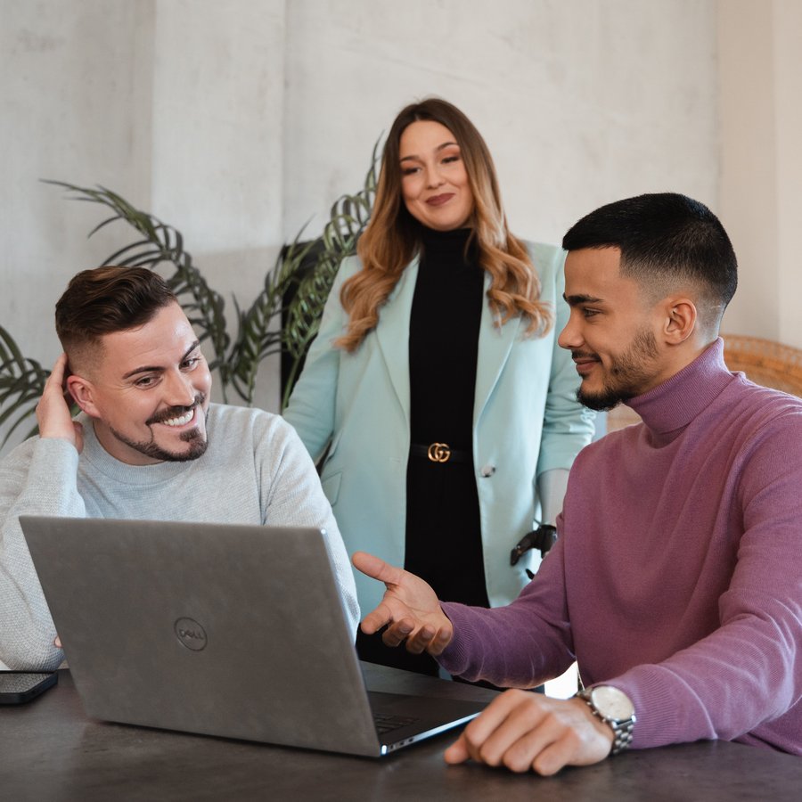 Drei Personen besprechen gemeinsam etwas am Laptop.
