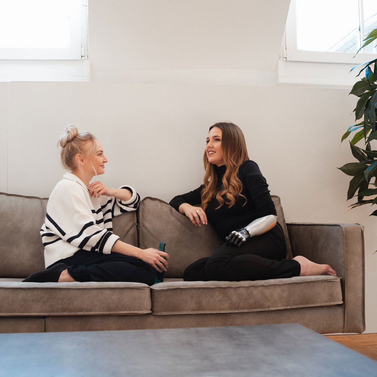 Zwei Frauen sitzen entspannt auf einem Sofa und unterhalten sich.