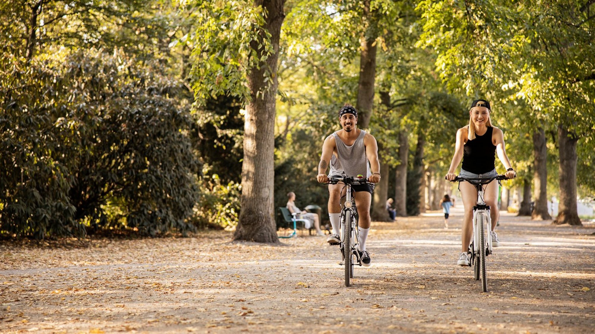 Two young people riding bikes in the park