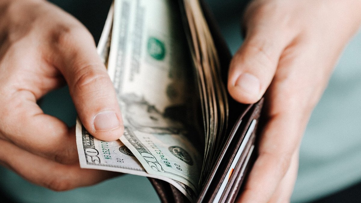 Hands opening a wallet with banknotes 