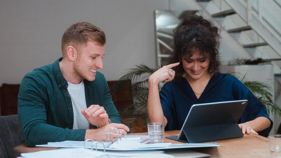 Mann und Frau sitzen am Tisch und betrachten Laptop