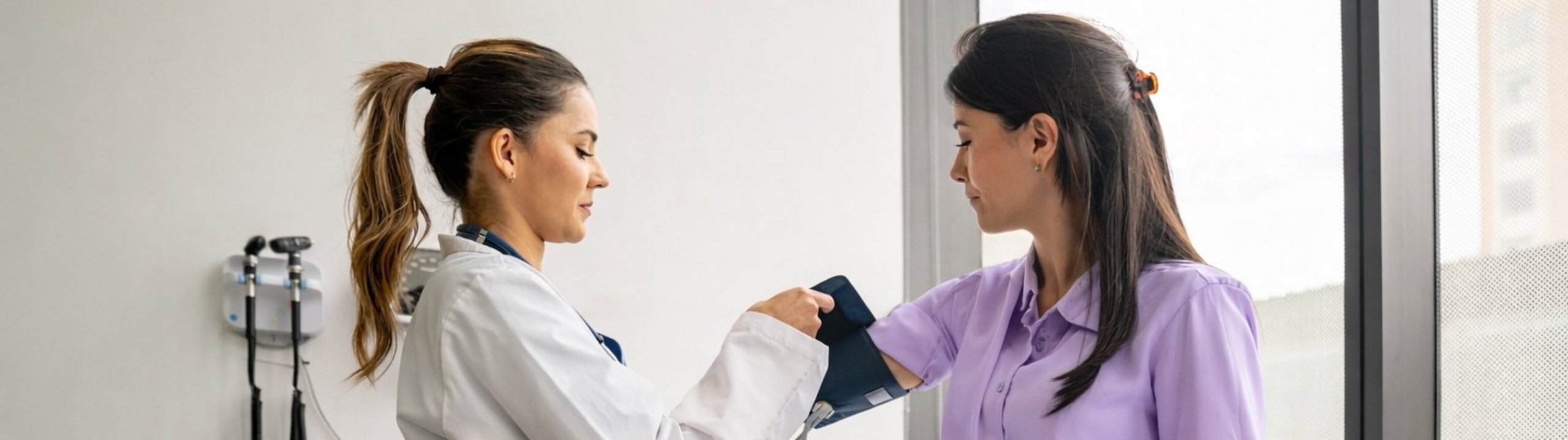 Ärztin misst den Blutdruck einer Patientin.