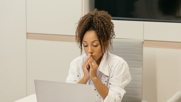 Junge Frau sitzt grübelnd vor Laptop – Resilienz 