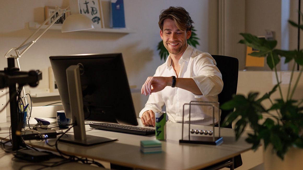 Man at his desk looks at the clock and starts his evening routine