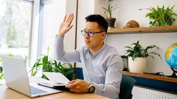 A man sits in an online meeting in his home office 