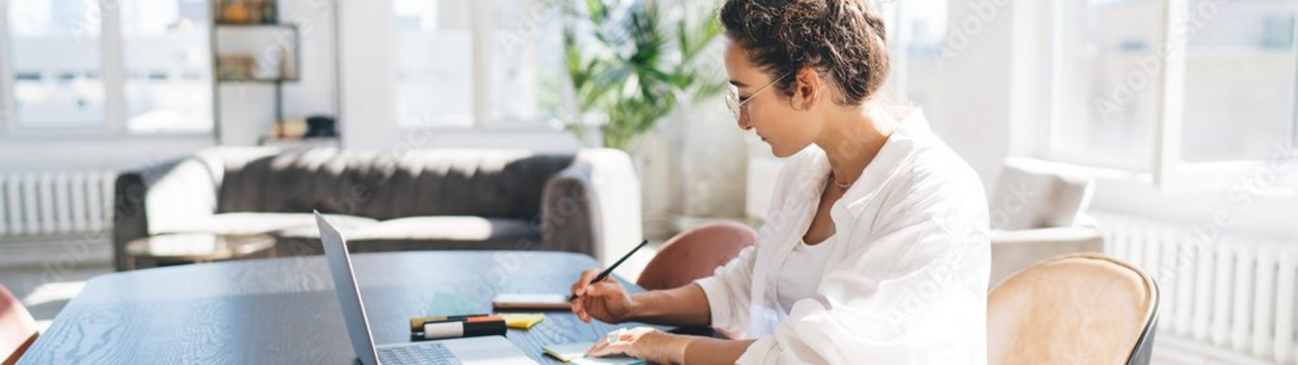 Eine Frau sitzt am Tisch, arbeitet und prüft ihren Fondssparplan