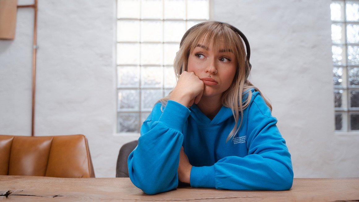 A young woman sits in thoughtful contemplation at a table