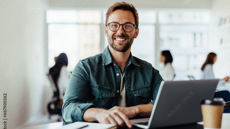 Eine lächelnde Person arbeitet an einem Laptop in einem modernen Büro.