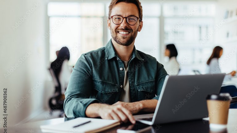 Eine lächelnde Person arbeitet an einem Laptop in einem modernen Büro.