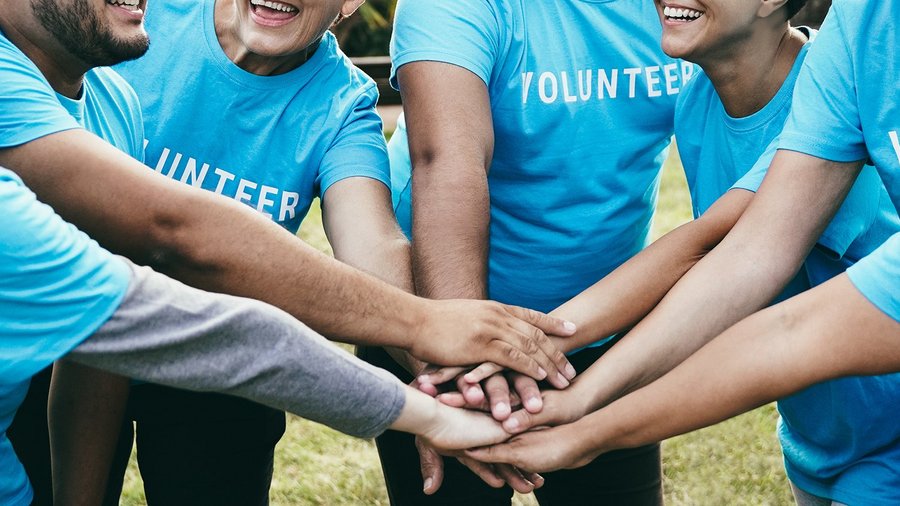 Gruppe freiwilliger Helfer hält die Hände zusammen