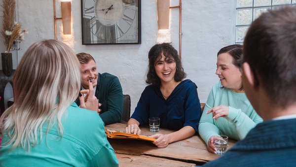 Team sitzt lachend im Meeting zusammen
