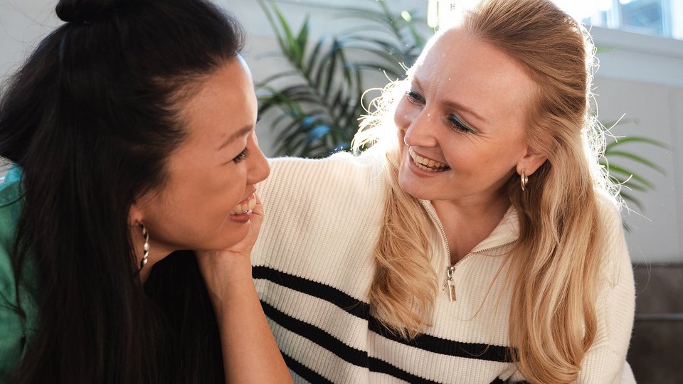 Zwei Frauen schauen sich lachend an