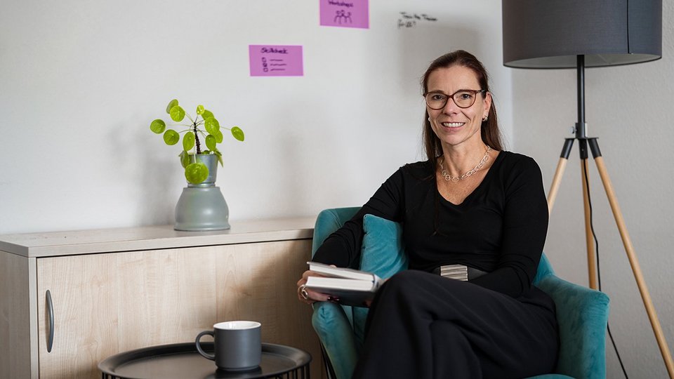 Petra Kuhlmann at OVB Holding sits in the office with a book