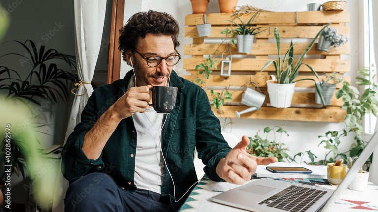 Mann sitzt mit Kaffee vor dem Laptop und ist im Gespräch.