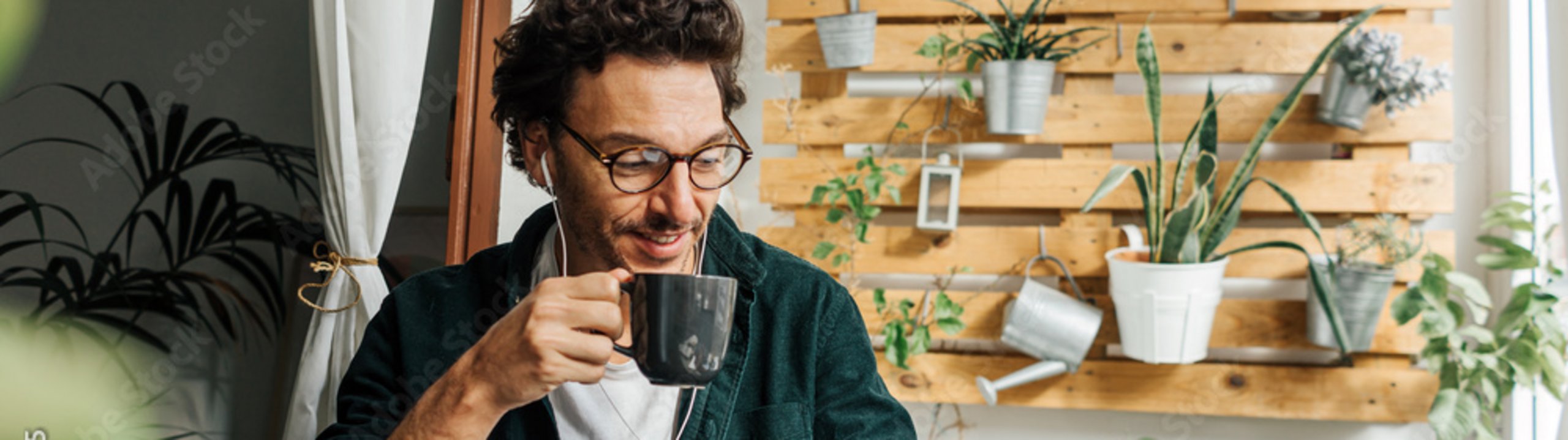 Mann sitzt mit Kaffee vor dem Laptop und ist im Gespräch.