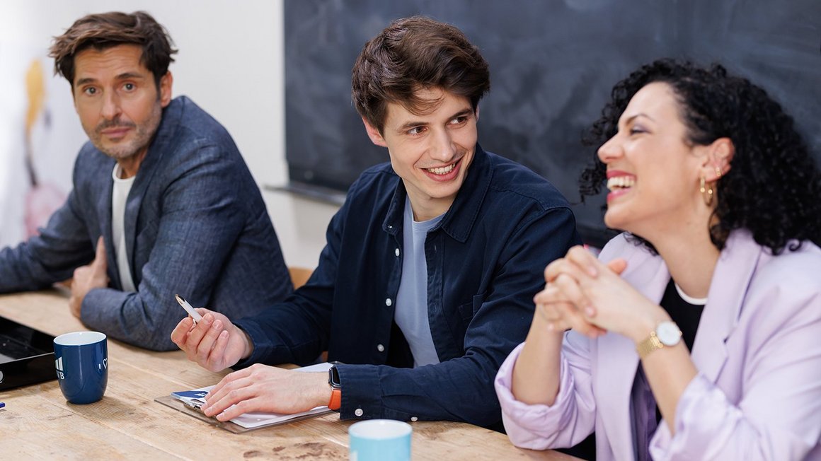 Team sitzt motiviert am Tisch und lacht