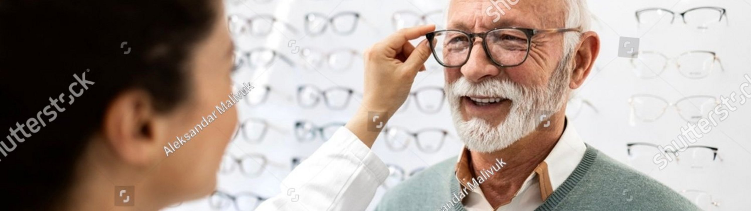 Optikerin passt einem älteren Mann eine Brille an.