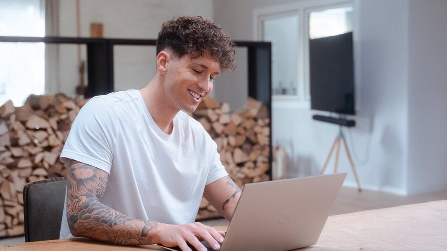 Young man working on a laptop, being happy after a career change