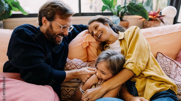 Familie kuschelt lachend auf dem Sofa.