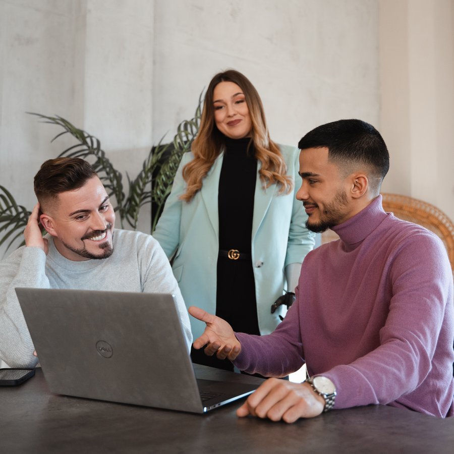 Drei Personen besprechen gemeinsam etwas am Laptop.