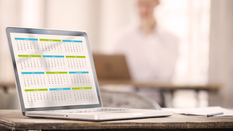 Laptop auf einem Tisch, der einen Kalender auf dem Bildschirm anzeigt.
