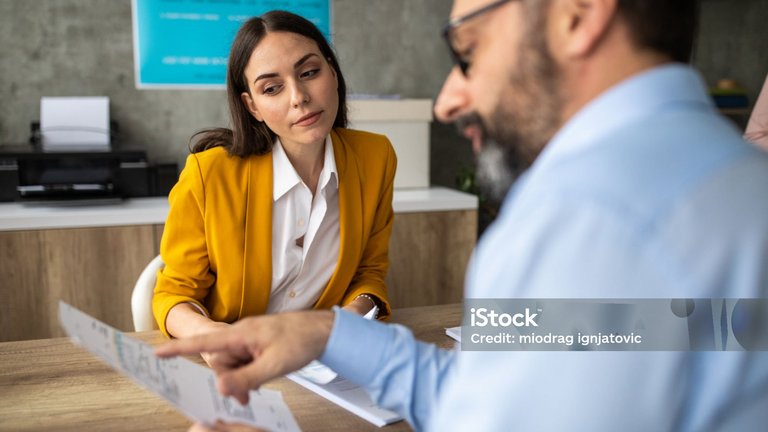 Eine Frau und ein Mann besprechen gemeinsam ein Dokument am Tisch.
