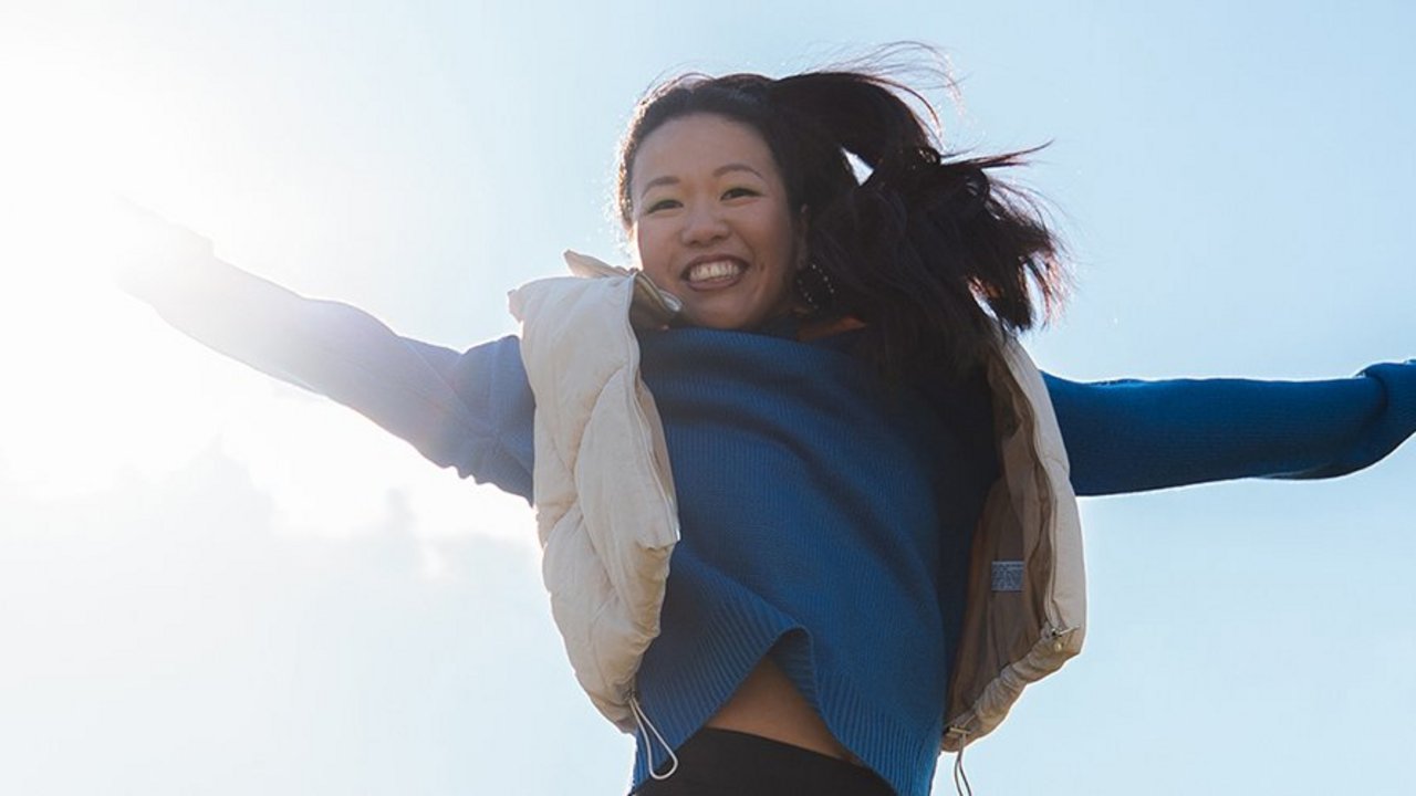 Woman jumping with outstretched arms into the sky