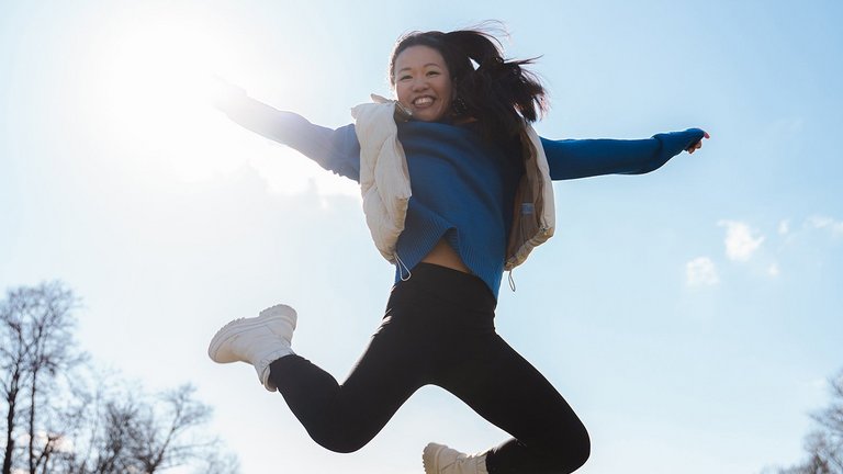 Woman jumping with outstretched arms into the sky