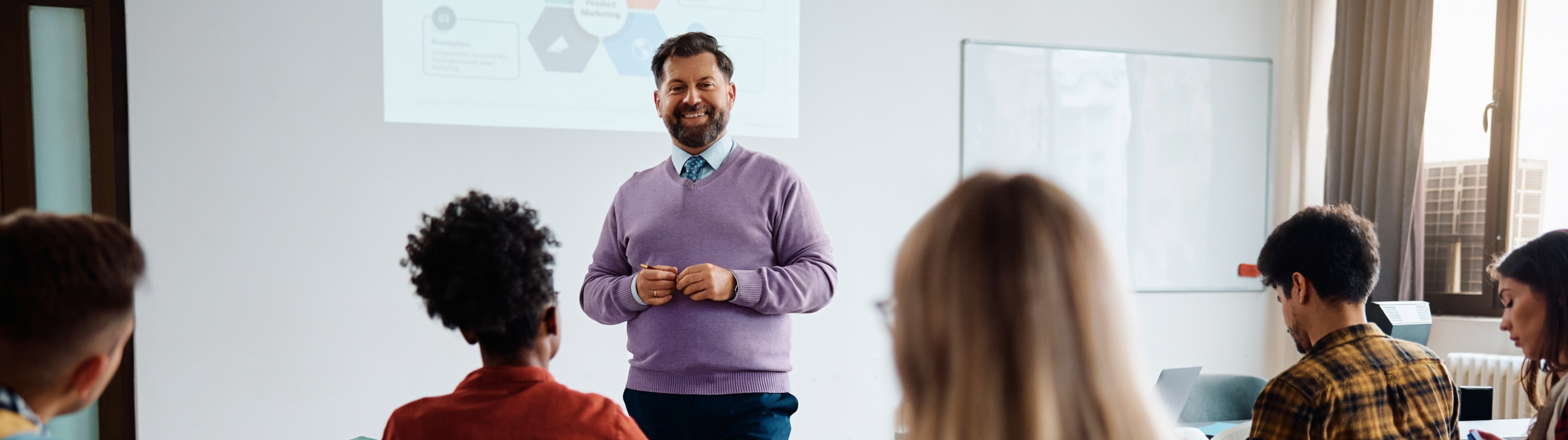 Ein Dozent hält einen Vortrag vor Studierenden in einem Seminarraum, während diese aufmerksam zuhören und Notizen machen.
