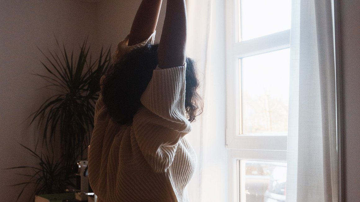 Woman stretches in front of the window for her morning routine