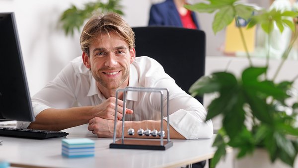 Sustainability Employee smiling at the workplace with ball pendulum