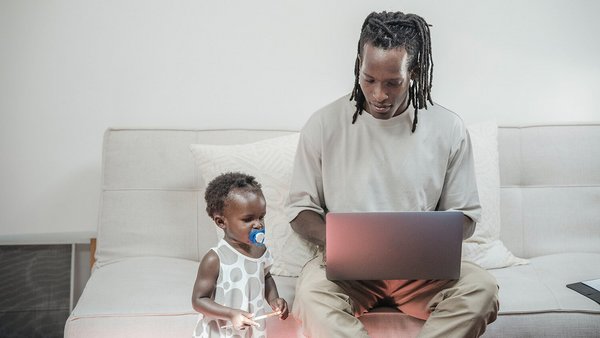 Papa arbeitet und Kind sitzt daneben – Vereinbarkeit von Familie und Beruf 